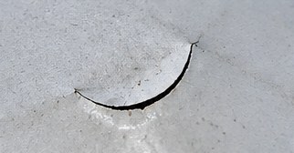 A small crescent-shaped cut in a TPO membrane