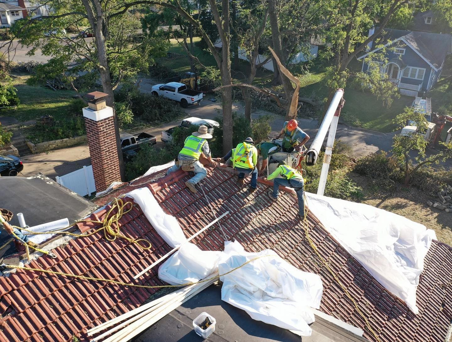 Crew shrink-wrapping a historic roof to keep rain out