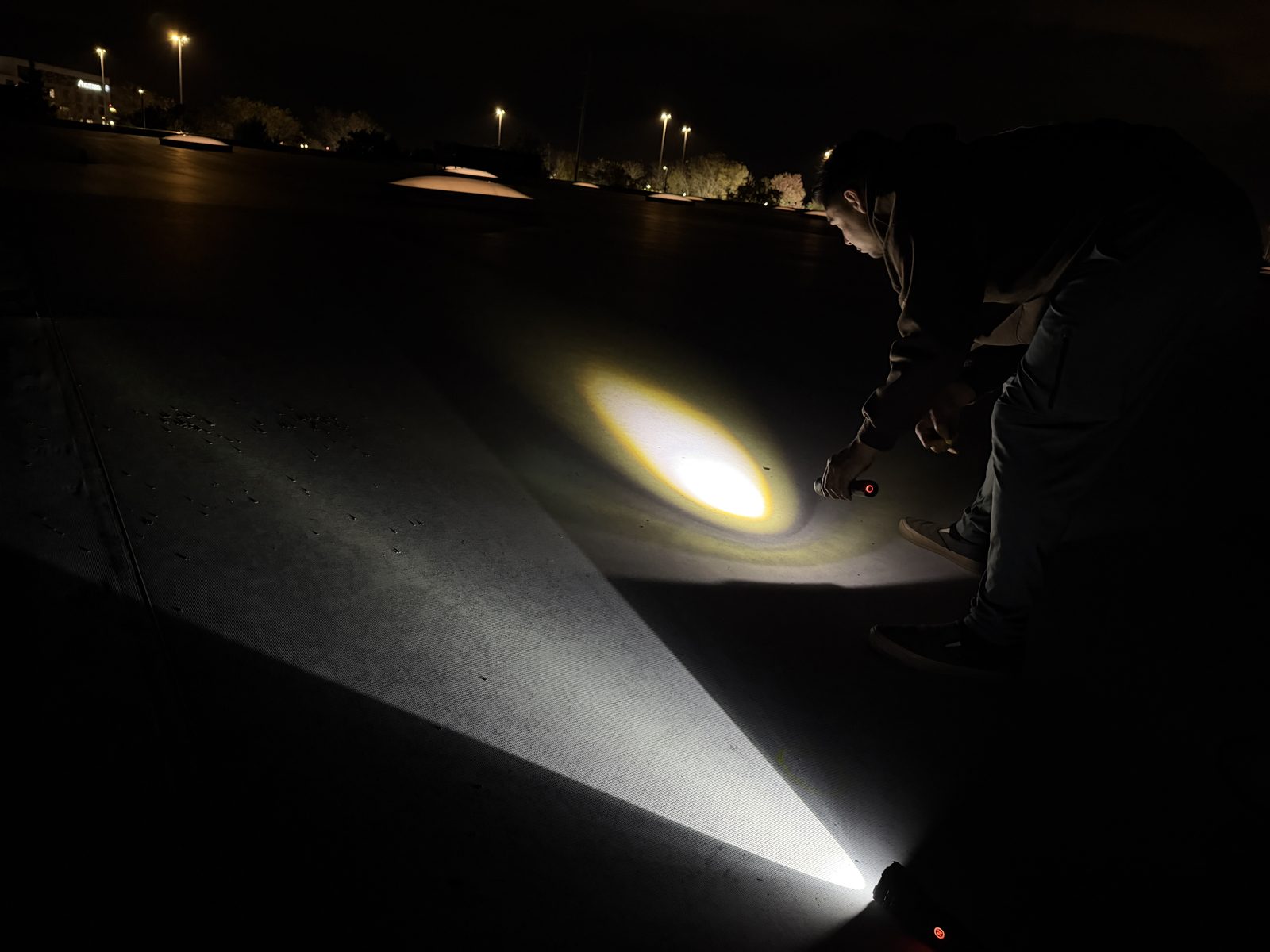 Close view of hail impacts lit by a flashlight on a flat roof at night