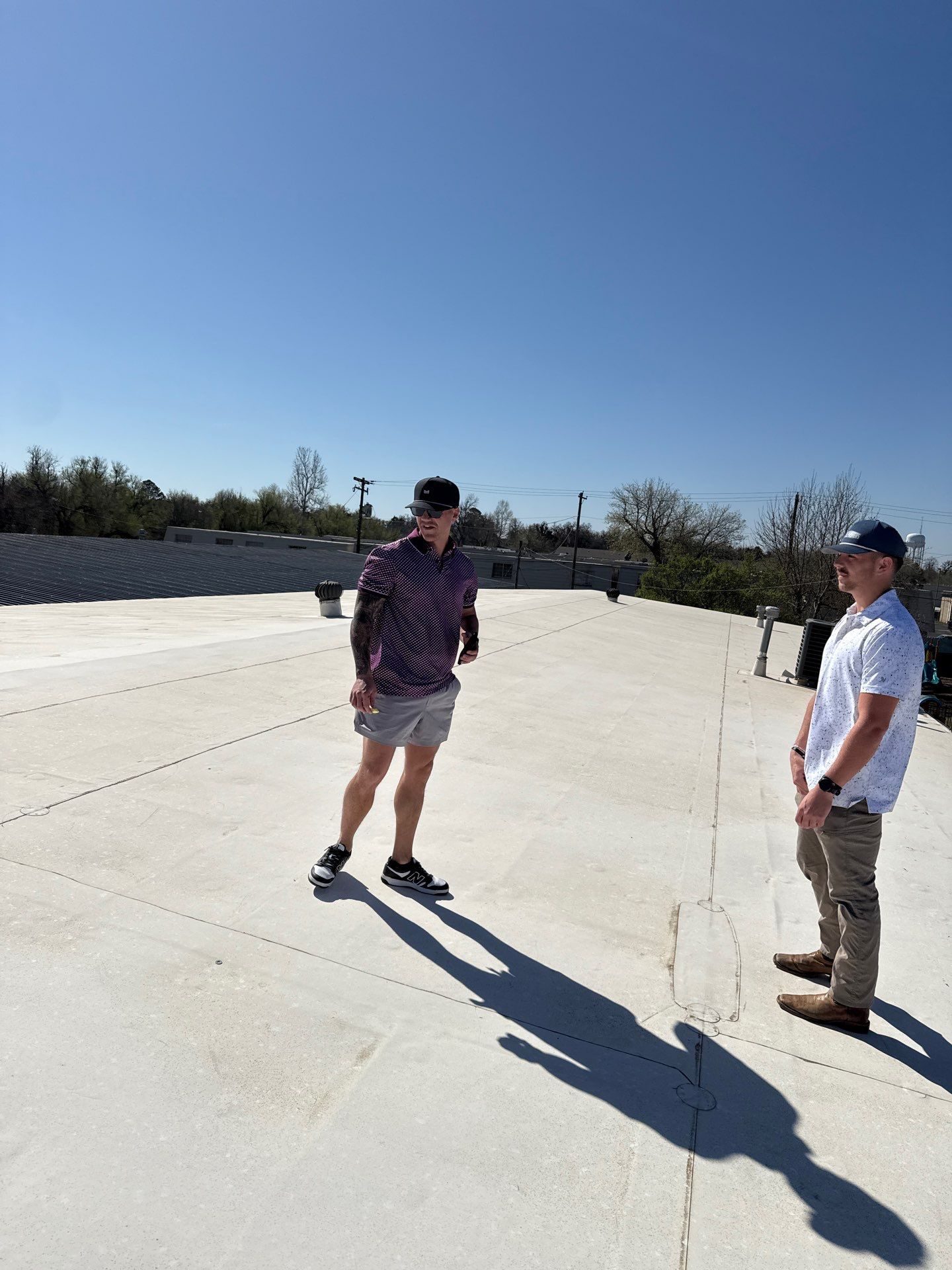 Two of our team walking a white flat roof after a hail storm