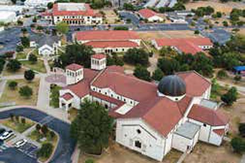St. William Catholic Church campus in Round Rock, Texas, with clay tile roofs and a copper dome, aerial view
