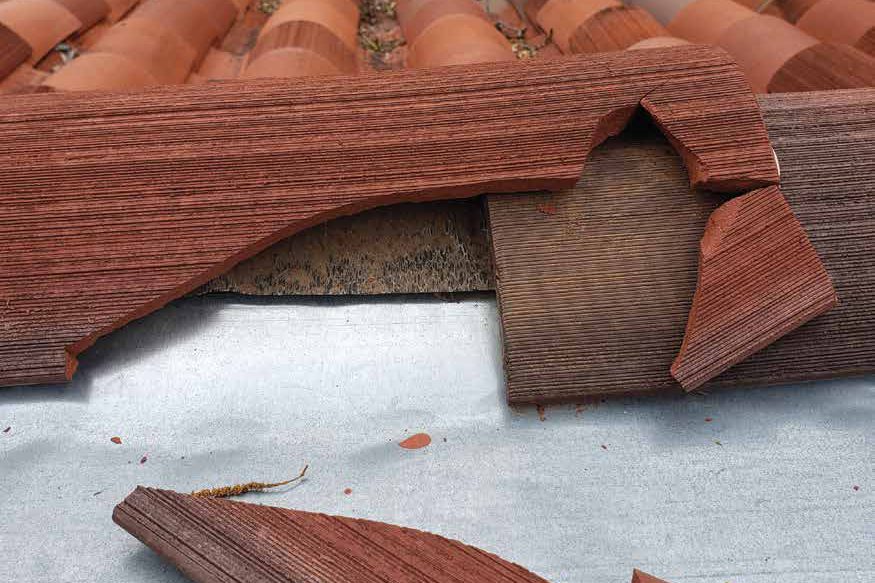 Broken clay tile lifted off the roof